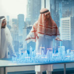 Business Developers in Traditional Clothes Discuss Investing Opportunities Based on Holographic Augmented Reality 3D City Model in Their Modern Office in a Skyscraper.