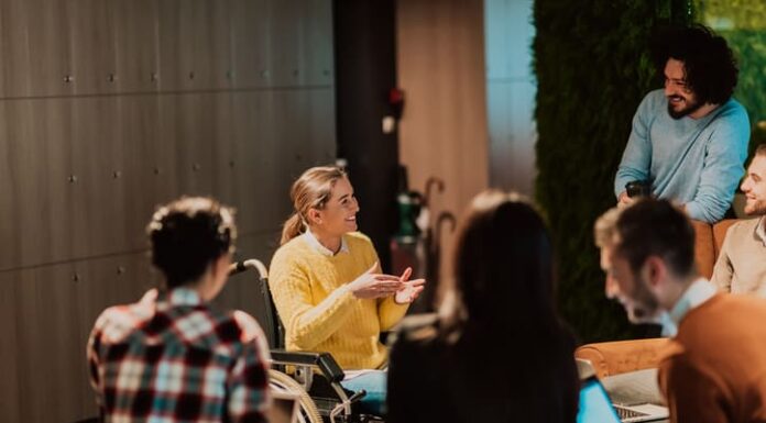 Businesswoman in wheelchair having business meeting with team at modern office.