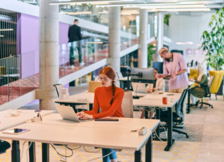 professional businesswoman with orange hair sitting at her laptop, epitomizing innovation and productivity in her contemporary workspace