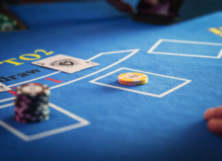 Anonymous Croupier Dealing Playing Cards on a Blackjack Table with Bet Chips in Place.