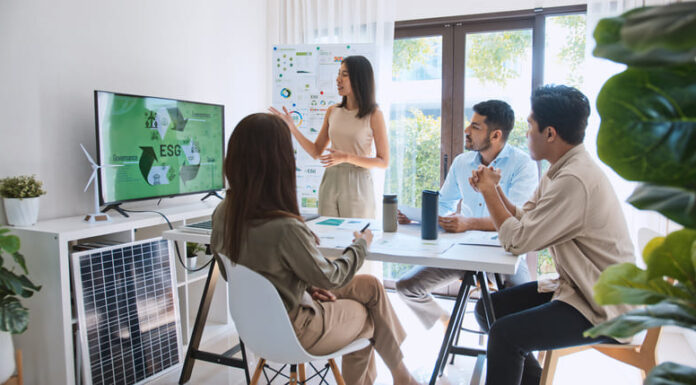Asian woman lead young group of multiethnic businesspeople in team meeting, using laptop computer for ESG topic presentation on monitor.