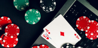 Why Online Casino is so Vastly Popular Today Red And Black Casino Chips On A Table With A Laptop And Playing Cards