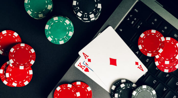 Why Online Casino is so Vastly Popular Today Red And Black Casino Chips On A Table With A Laptop And Playing Cards