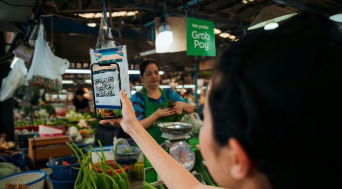 The Mobile-First Consumer: Navigating the Evolving E-commerce Landscape Woman holding up a smart phone in a market