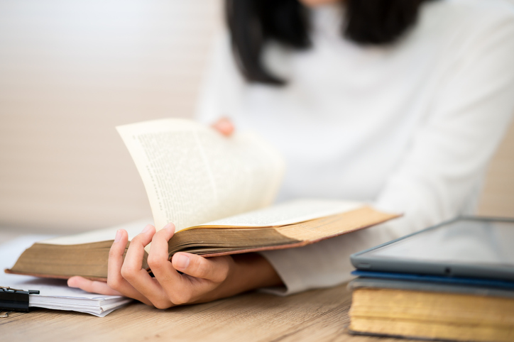 woman wearing a white shirt sitting and reading 