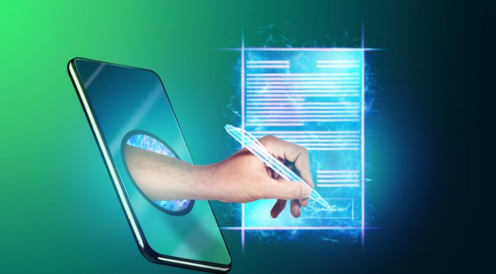 Automating Employment Contracts: A Practical Approach to Streamlined HR Operations Image of a phone and a hologram of a contract and a hand with a pen for signature.