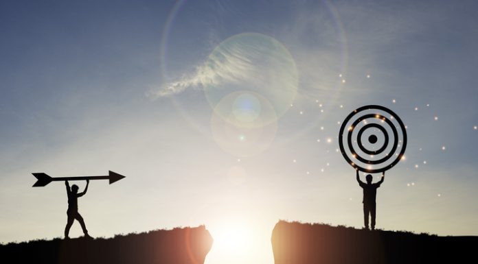 The Dangers of Being Outcome-Obsessed Silhouette men throwing arrow and holding dartboard on mountain with blue sky and sunlight for achievement objectives target and vision