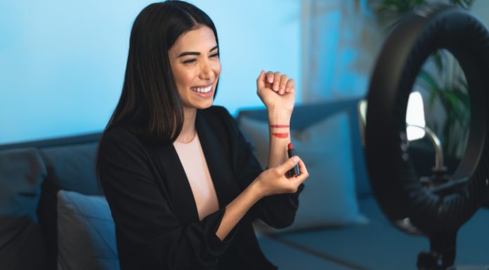 Female makeup influencer vlogging online with smartphone cam and ring led from home