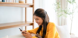 Thinking of You Messages: Ideas to Brighten Someone’s Day Woman texting messages relaxing on couch in cozy living room at home