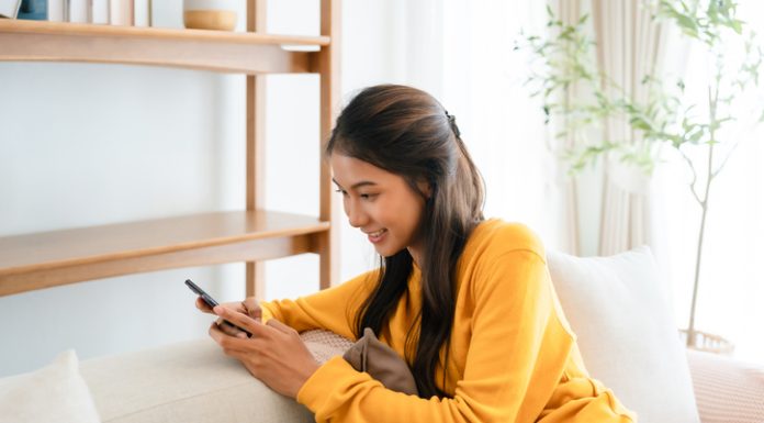 Thinking of You Messages: Ideas to Brighten Someone’s Day Woman texting messages relaxing on couch in cozy living room at home