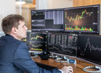 Stock trader looking at computer screens in trading office