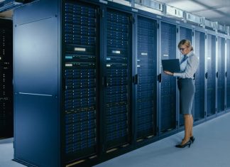 Client Server Networks: What are they, and what are the Advantages? Female IT Technician Stands Near Rack Cabinet and Runs Maintenance Program on Laptop, Controls Operational Server's Optimal Functioning.