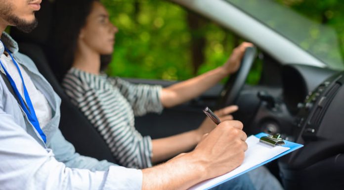 What Happens If You Fail the Theory Test in Norway? Cropped of male instructor examinating female student, taking notes at test chart while sitting by young woman driving automobile, side view, copy space, closeup.