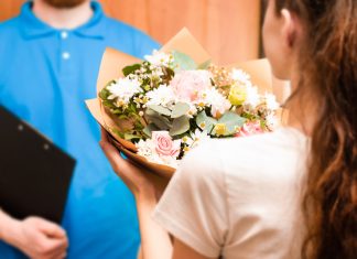 courier hands bouquet to young woman, flower delivery