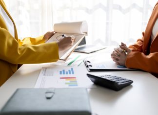 Business women working on desk office with using a calculator to calculate the numbers tax, finance accountingresearch or financial strategy in company