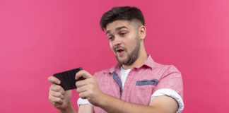 Digital Platform Security: Consumer’s Guide for Safe Casinos and Betting Online Young man wearing pink polo playing game on mobile phone