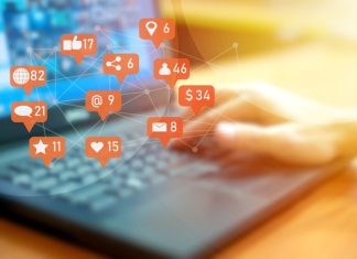 Businessman using laptop with social media notifications on screen