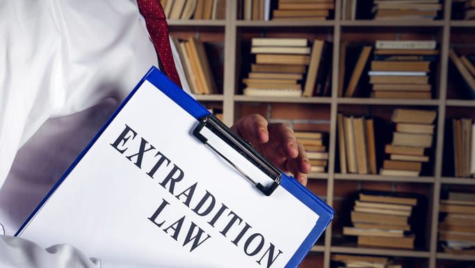 Immigration lawyer holds extradition law with clipboard.