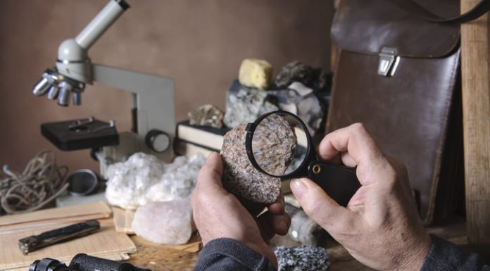 Geologist examining a mineral sample under a magnifying glass