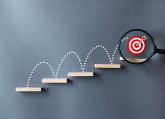 Unlock potential and strategy of business success stairs dart and dartboard targets magnifying glass with hand on gray background.