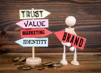 The Psychology Behind Why Some Brands Instantly Gain Trust Miniature holding road sign arrows with brands written on wood texture background