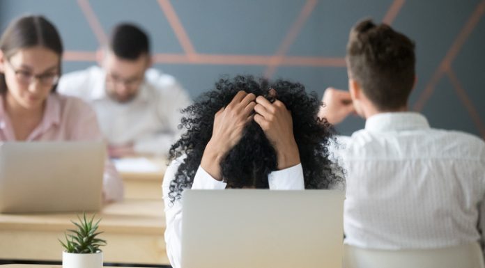 Frustrated african-american woman feeling burnout in shared office with laptop