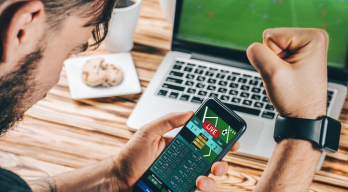 Lucky man celebrating victory after making bets on ICCWIN using gambling mobile application on his phone.