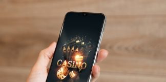 In the hands of a smartphone with playing cards the inscription casino, black-gold background.