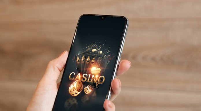 In the hands of a smartphone with playing cards the inscription casino, black-gold background.