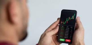 Middle-eastern businessman using trading application on smartphone for prop trading