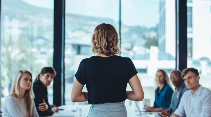 Woman addressing a meeting in office boardroom.