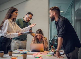 Stressed annoyed office employee manager having headache migraine at business meeting with his colleagues about business problem they have to solve.