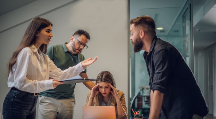 Stressed annoyed office employee manager having headache migraine at business meeting with his colleagues about business problem they have to solve.