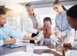 Emotional colleague being comforted by manager and co-workers