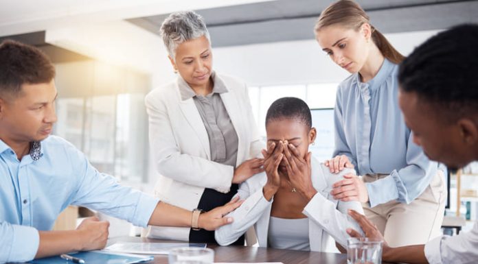 Emotional colleague being comforted by manager and co-workers