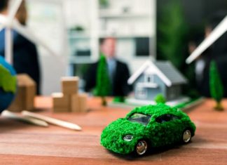 EV car model on table with blurred business people planning business marketing for eco-friendly car in background. Greener future with alternative energy charge utilization in business