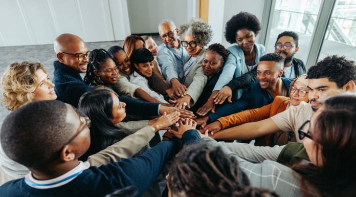 Multiethnic business colleagues displaying teamwork and unity by joining hands together. Emphasizing diversity, collaboration, and community in a modern workplace.