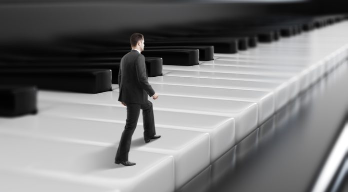 Side view of young businessman walking on abstract piano keys. Music, show business concept.