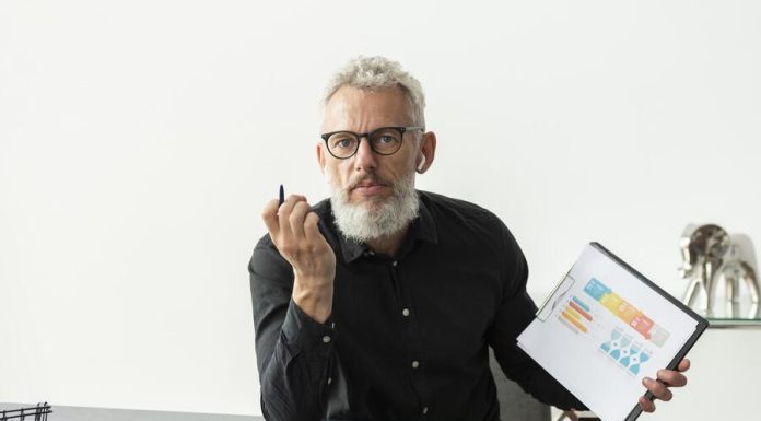 Older man at home showing graph on notepad with tablet on desk for traditional budgeting