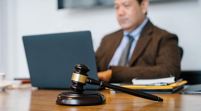 Seven Questions to Ask Your Personal Injury Lawyer A male lawyer in a brown suit on his computer typing with a gavel front and center on his desk.