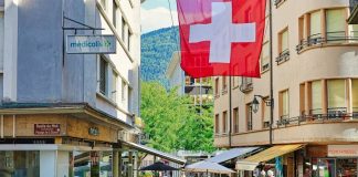 A red and white flag flying over a city street. Nutri-score in Switzerland