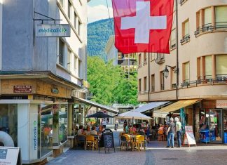 A red and white flag flying over a city street. Nutri-score in Switzerland