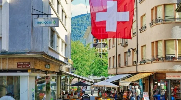 A red and white flag flying over a city street. Nutri-score in Switzerland