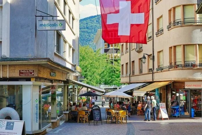 A red and white flag flying over a city street. Nutri-score in Switzerland
