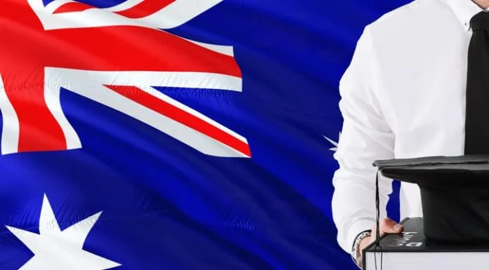 Holding books and graduation cap over Australia flag