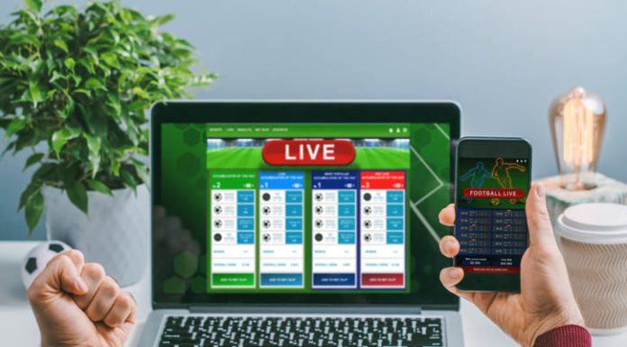 Man using his laptop and smartphone for making research on bets online at bookmaker's website and mobile application.