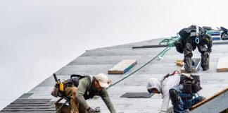 Crew Installing New Shingles on Roof on a Rainy Day