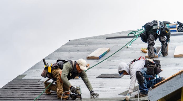 Crew Installing New Shingles on Roof on a Rainy Day