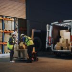 Outside of Logistics Retailer Warehouse With Female Manager Using Tablet Computer, Worker Loading Delivery Truck with Cardboard Boxes and materials