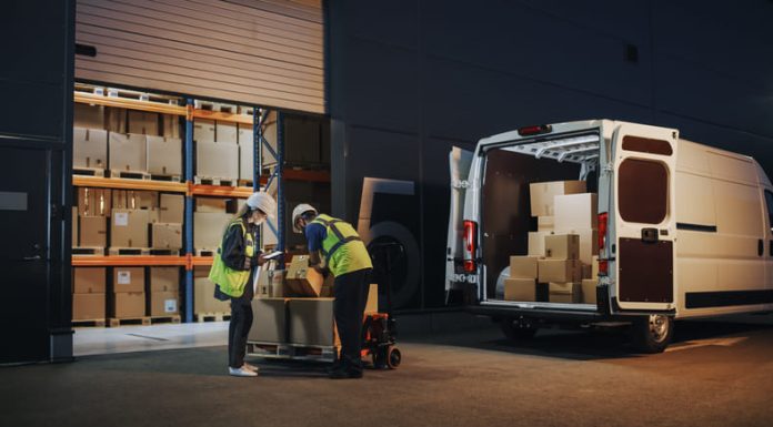 Outside of Logistics Retailer Warehouse With Female Manager Using Tablet Computer, Worker Loading Delivery Truck with Cardboard Boxes and materials